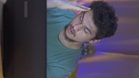 Vertical-video-of-Man-getting-tired-while-using-computer-at-night.